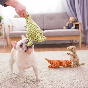 Detailed view of a French Bulldog playing with textured plush dinosaur toys in a home setting