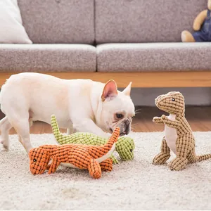 French Bulldog puppy playing with colorful dinosaur squeaky plush toys on cozy carpet.
