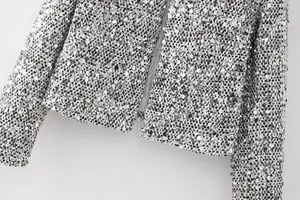 Close-up detail of silver sequined tweed jacket showing intricate woven texture and shine