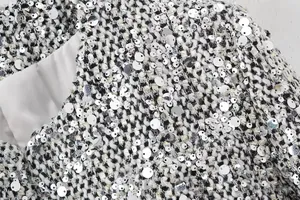 Close-up macro shot of shimmering silver sequins on premium black and white tweed fabric