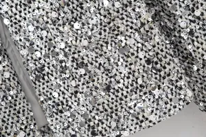 Macro detail of black and white tweed fabric with shimmering silver sequins.