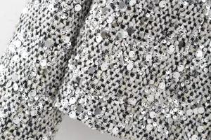 Close-up detail of silver sequins on a premium black and white tweed blazer jacket