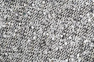 Detailed macro view of shimmering silver sequins on high-quality tweed fabric texture.