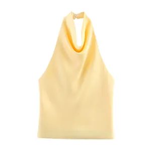 Detail van de elegante gedrapeerde halslijn en halterkraag van deze gele satijnen top.