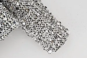 Detailed view of shimmering silver sequins on black and white textured tweed jacket fabric