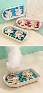 Slow feeder dog bowl with shell pattern, shown being used by a white fluffy dog.