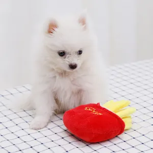 Simpatico cucciolo accanto a un giocattolo di peluche a forma di patatine fritte rosse