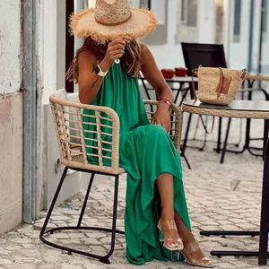 Stylish green sleeveless halter maxi beach dress shown on a model in an outdoor cafe