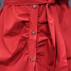 Macro view of red shirt dress with ruched detail, brown buttons and matching waist belt.