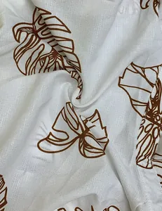 Detalle de estampado de hojas de monstera marrón sobre tela blanca con textura de lino