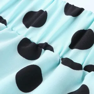 Close-up detail of mint blue fabric featuring large black polka dots and elastic waist