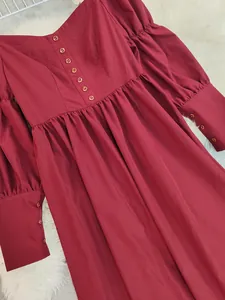 Détail d'une robe vintage bordeaux avec des boutons élégants et des poignets