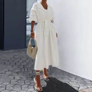 Elegante witte midi trenchcoat jurk met lange mouwen en riem gedragen op straat