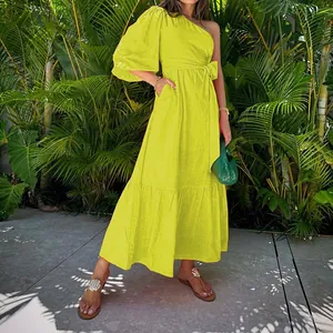 Vibrant yellow one-shoulder tiered cotton linen midi dress styled with a green bag in a garden