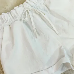 Detail of white cotton linen casual shorts featuring elastic waistband and drawstring tie.