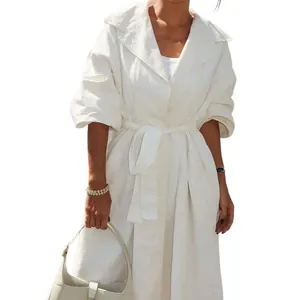 Detail van de textuur van de witte halflange trenchcoat met lange mouwen en een ceintuur