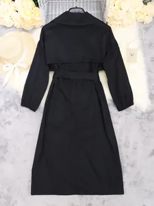 Gedetailleerd achteraanzicht van een elegante zwarte lange trenchcoat met ceintuur.