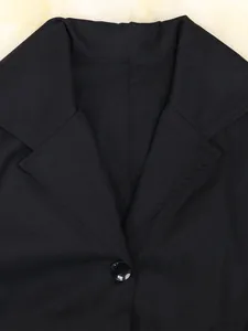 Detailopname van de reverskraag en knoop van een zwarte windjack voor dames.