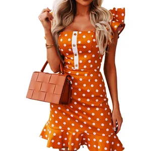 Detailed view of an orange polka dot dress with ruffle sleeves and button accents