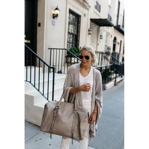 Loose longline knit cardigan with asymmetrical hem worn by model in street setting