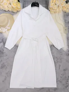 Gedetailleerd zicht op een elegante witte midi trenchcoat met lange mouwen en riem.