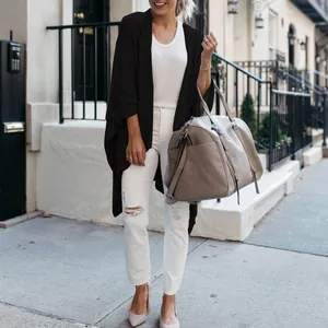 Woman wearing black long-line knit cardigan with irregular hem in urban street setting