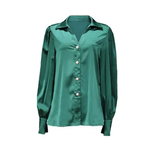 Detailed view of emerald green satin blouse with star buttons and puff sleeves