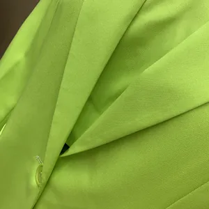 Macro detail showing the lapel and fabric texture of a vibrant lime green tailored blazer