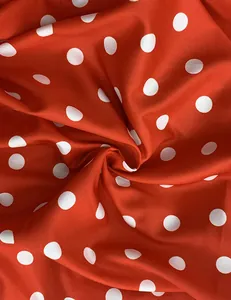Close-up of vibrant red fabric with classic white polka dots for summer fashion.