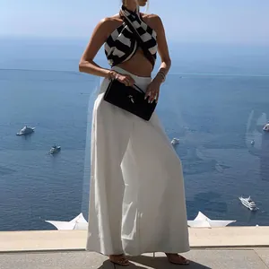 Full-body view of elegant white wide-leg trousers worn by a model at a seaside resort