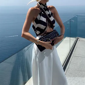 Lifestyle detail showing white high-waisted wide-leg pants in a coastal resort setting.