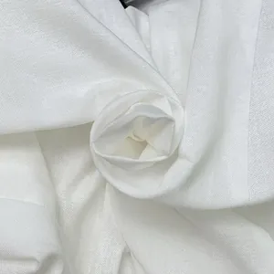 Close-up of premium white cotton linen fabric texture with an elegant floral fold detail.