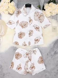 Detalle de un conjunto de dos piezas blanco con estampados de hojas tropicales café.