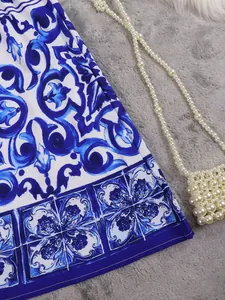 Detail view of blue and white floral print skirt with elegant pearl bag prop.