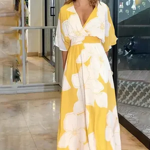 Detailed view of a yellow floral maxi dress featuring a V-neck and cinched waist for beach wear