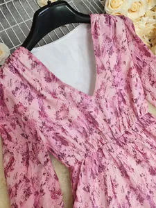 Close-up detail of a pink bohemian V-neck dress featuring an abstract floral print pattern