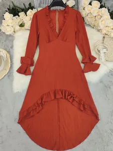 Detail van de elegante roestrode jurk met lange mouwen, ruches en een crêpetextuur