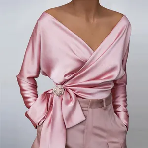 Close-up of elegant pink satin wrap blouse with side-tie and decorative brooch