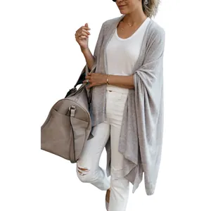Detailed view of women's loose grey knit cardigan featuring an asymmetric hemline design
