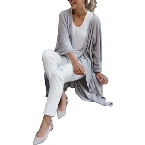 Close-up detail of women's loose light gray knit cardigan featuring an irregular hemline