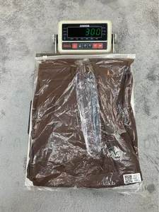 Close-up of brown high-waisted trousers being weighed on a digital scale in packaging