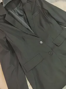 Detailed macro shot of a black casual blazer showing button and pocket details.