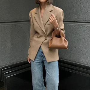 Eleganter khakifarbener Damen-Blazer, kombiniert mit Jeans und einer braunen Handtasche.