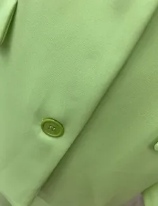 Macro detail view of light green suit jacket showing fabric texture and matching button