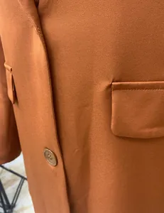 Close-up of burnt orange blazer showing fabric texture, pocket flap, and button detail
