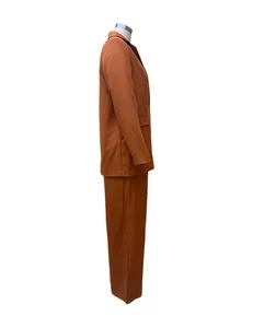 Side profile view of a women's elegant solid rust brown two-piece blazer and pants set.
