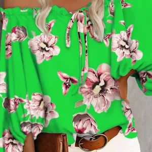 Detailed view of vibrant green off-the-shoulder blouse featuring elegant pink floral patterns
