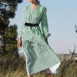 Model wearing a green and white striped V-neck midi dress in a natural outdoor setting