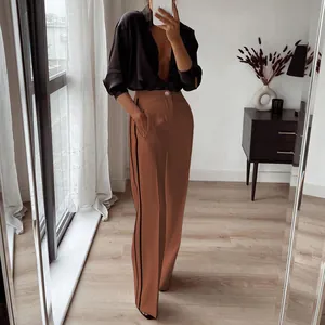 Detailweergave van een bruine rechte broek met hoge taille en zwarte zijstrepen
