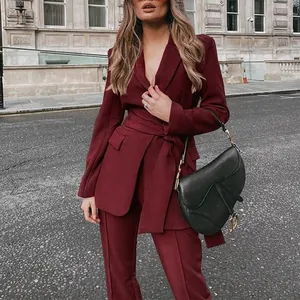 Elegante vrouw in bordeauxrood tweedelig pak met ceintuur in de stadsstraat